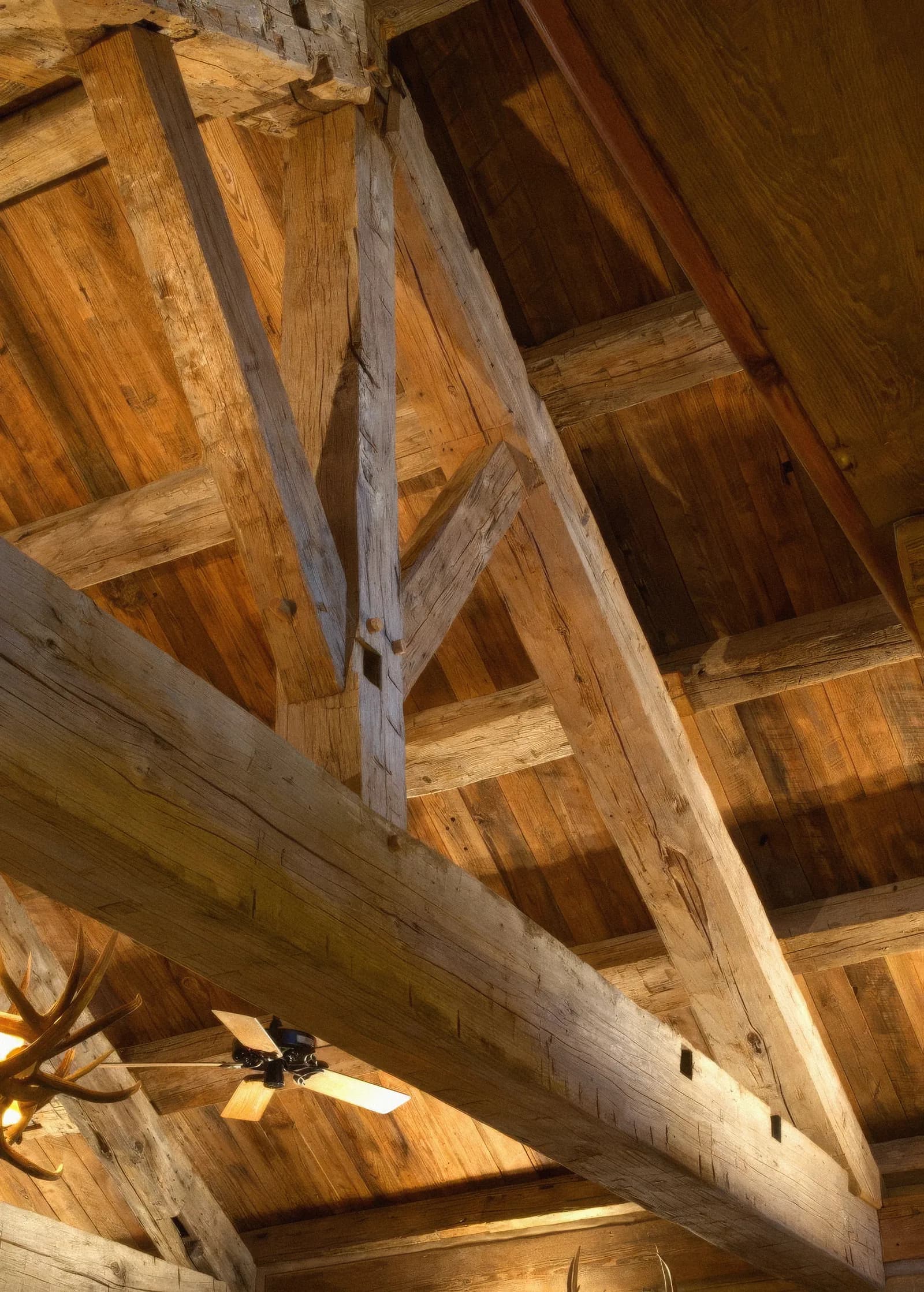 Hand hewn reclaimed oak trusses under a timber ceiling, seen from below