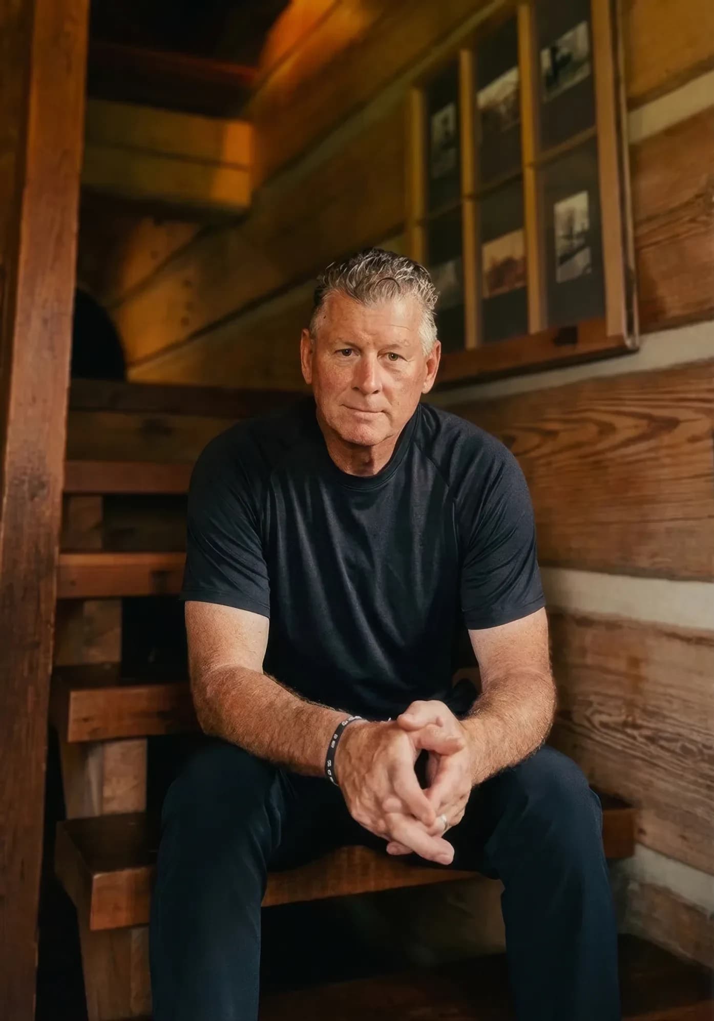 Shawn Burks, owner and president, seated on a reclaimed timber stair